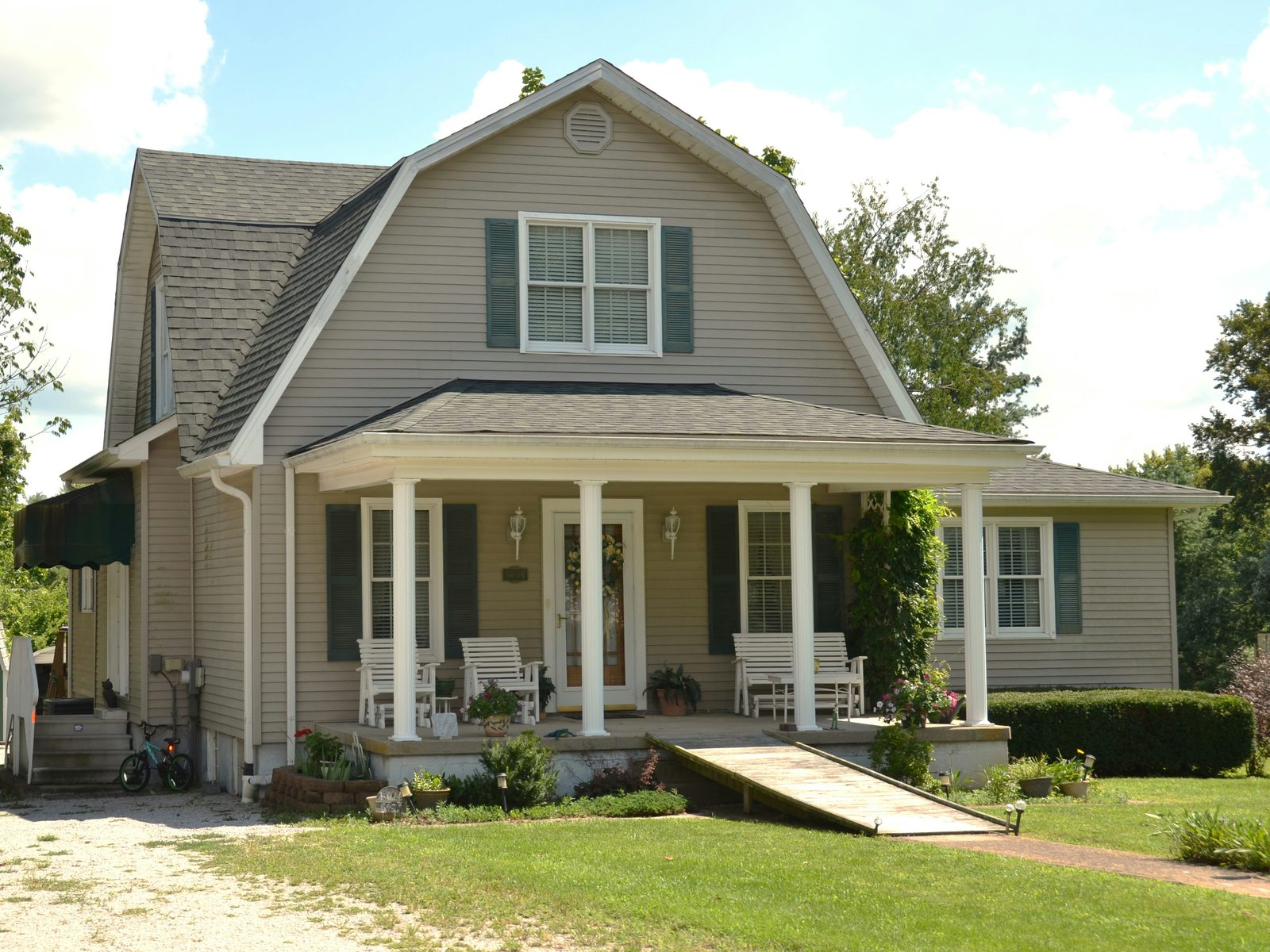 A house with a gambrel roof and a deep front porch with rocking chairs
