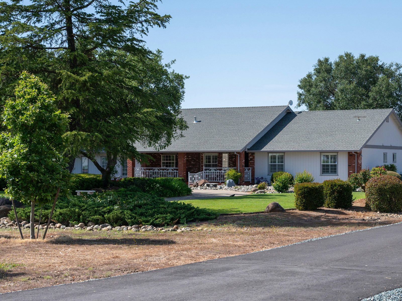 A brick ranch home with mature planting along the front garden