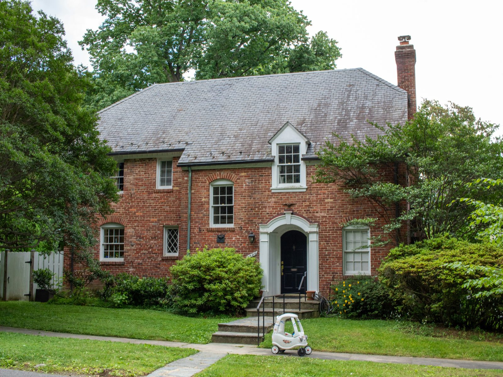 A brick two-storey home with a slate roof and an arched front door