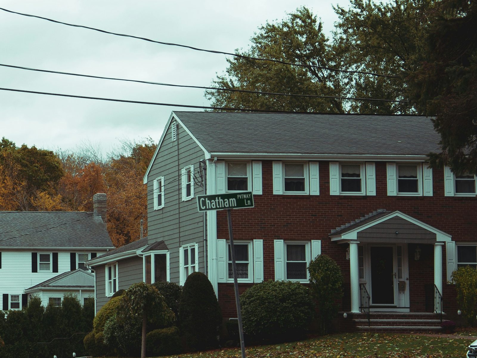 A two-storey colonial home on a quiet street lined with autumn trees